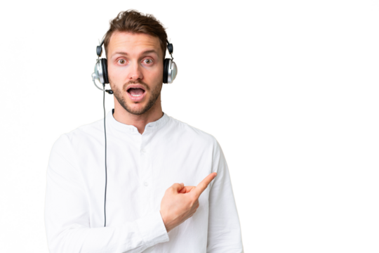 Telemarketer caucasian man working with a headset over isolated chroma key background surprised and pointing side