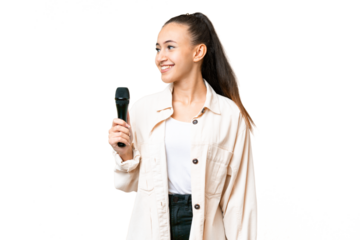 Young singer woman picking up a microphone over isolated chroma key background looking side
