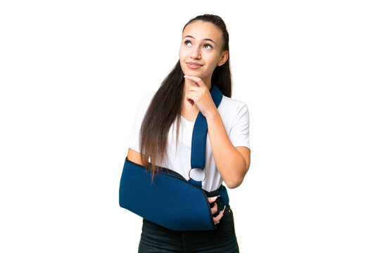 Young Arabian woman with broken arm and wearing a sling over isolated chroma key background and looking up