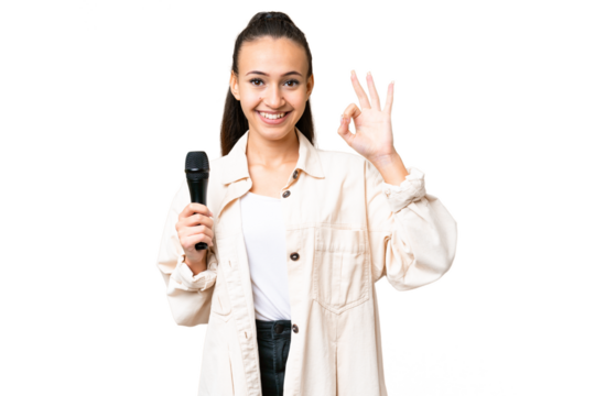 Young singer woman picking up a microphone over isolated chroma key background showing ok sign with fingers