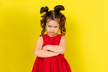 The little girl was offended. a child in a beautiful red dress pouted her lower lip. Yellow...