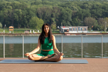 Portrait Of Athletic Middle Aged Female Training Outdoors, Making Butterfly Stretch Exercise, Sporty Beautiful Woman Sitting On Yoga Mat On Wooden Pier Near River And Smiling At Camera, Copy Space