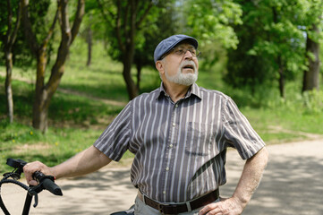A positive, charismatic elderly man on an eco scooter went for a walk in the park. Healthy lifestyle of the elderly.