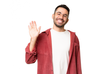Young handsome caucasian man over isolated chroma key background saluting with hand with happy expression