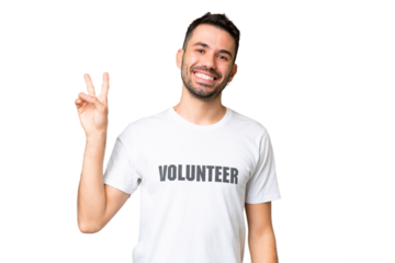 Young volunteer caucasian man over isolated chroma key background smiling and showing victory sign