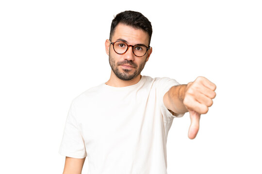 Young handsome caucasian man over isolated chroma key background showing thumb down with negative expression