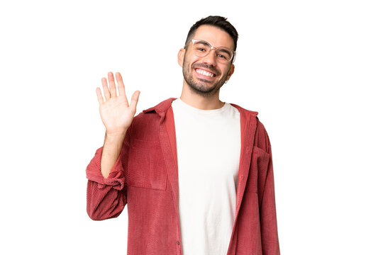Young handsome caucasian man over isolated chroma key background saluting with hand with happy expression