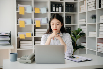 Young beautiful woman typing on tablet and laptop while sitting at the working wooden table office.