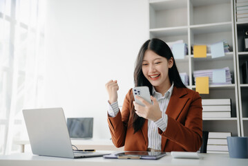 Asian business woman are delighted and happy with the work they do on their tablet, laptop and taking notes at office...