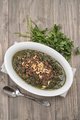Oriental food of mulukhiyah topped with minced meat and pine seeds, Molokhia Arabian food , spinach with minced meat