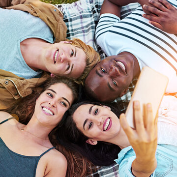 Friends, top view and outdoor for circle selfie, happiness and diversity for social media post, app or blog. Men, woman and youth for photography, profile picture and bonding while lying on ground