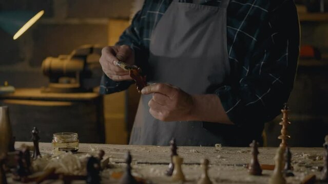 Carpenter, Middle-aged man Skillfully Painting wood with protective paint In the workroom Steady camera movement Furniture assembly worker Working with wood pieces In a craftsman's workshop, forestry
