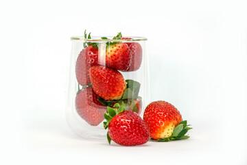 Fototapeta na wymiar Glass of fresh ripe strawberries on white background with copy space for text. Sun glare on the berry and glass
