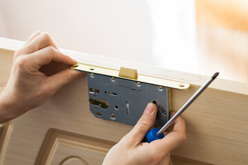 Handyman installing, repairing the door and lock. Closeup of worker hands installing new door lock. - 604305609