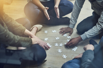 Hands, business people and puzzle in circle, solution and teamwork for problem solving, planning and games. Group, together and innovation with support, synergy and team building on office floor