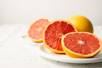 Obraz na płótnie Canvas View of cut red grapefruits with selective focus, on white tablecloth, white background, horizontal, with copy space