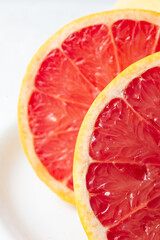 Macro close up of half a red grapefruit with selective focus, white background, vertical