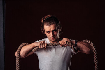 a young man stands with a thick rope in his hands