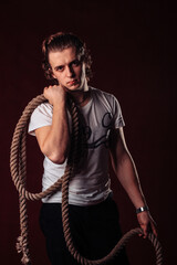 a young man stands with a thick rope in his hands