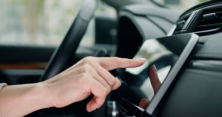 Close up shot hand of woman using touch screen in car setting up the navigation gps application on...