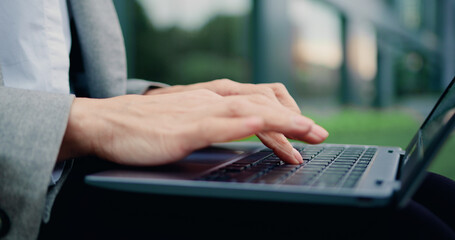 Closeup hands of happy skilled successful business lady staying at the street using laptop outdoor typing.