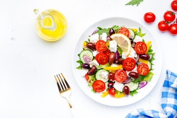 Traditional greek salad with feta cheese, kalamata olives, tomatoes, paprika, cucumber and onion, healthy mediterranean diet food. White table background, top view