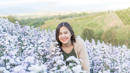 Asian woman stands among a violet margaret flower. - 604310039