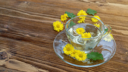Yellow chrysanthemum flower tea on a wooden table. - 604310061