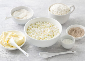 Ingredients for cottage cheese cookies: cottage cheese, butter, flour, sugar, vanilla sugar, salt, baking powder on a light gray background for delicious homemade baking
