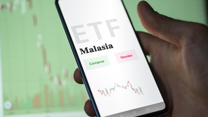 An investor analyzing an etf fund. ETF text in Spanish : Malaysia, buy, sell.