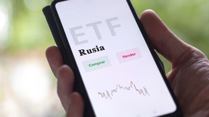 An investor analyzing an etf fund. ETF text in Spanish : Russia, buy, sell.