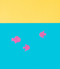 Minimal concept of beach. Glittering pink fishes swimming in the sea. Summer background. Copy space. Flat lay.