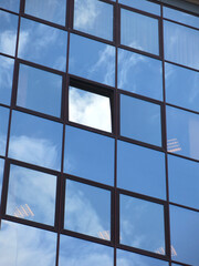 sky is reflected in the glass windows of the business center
