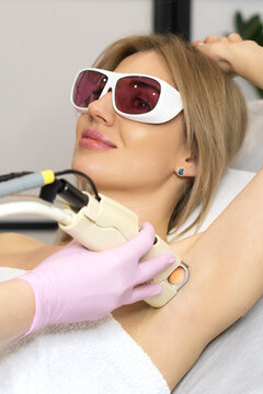 Close up Young smiling beautiful woman getting armpit laser hair removal procedure. the concept of skin and body care in the spa salon. permanent hair removal. vertical