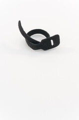 immagine primo piano con fascetta in materiale velcro per serrare, ordinare cavi su superficie di lavoro bianca