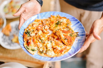 A hand holding a plate with a vegan pizza on it, vegetarian food and healthcare concept.