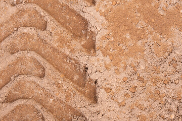 Footprint of car tire tread in a sand gravel road texture. Country road textured background. Backdrop for various ideas. Small stones land. Abstract sandy rough surface. Trendy effect. No people. Tyre