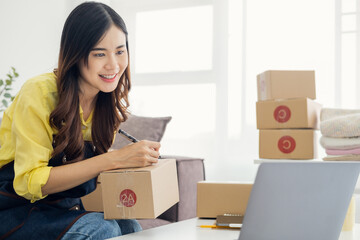 Young entrepreneur, teenager business owner work at home, alpha generation life style. Business woman online seller write down address on parcel box for deliver