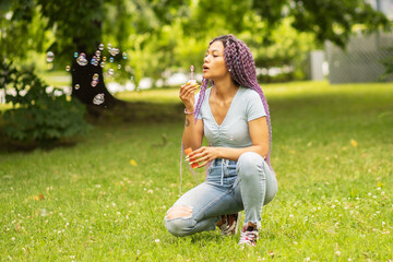 a woman in the park plays with children, blows soap bubbles on nature, has fun, rests on vacation