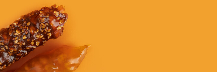churchkhela, Walnut and grape juice candy on an orange background, copy space, banner