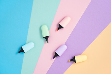 Stationery background with pastel color highlighter markers on pink, blue, yellow, green and purple. Flatly, copyspace.
