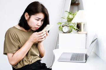 Kyphosis concept with a side view of Asian woman looking at a mobile phone with incorrect posture hunched back, forward head, and spinal curvature - obrazy, fototapety, plakaty