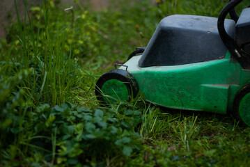 View of lawn-mower on green grass in the garden

