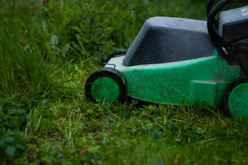 Close up of lawn-mower on green grass in the garden
