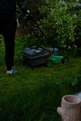 View of man near lawn-mower on green grass in the garden
