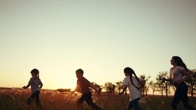 silhouette of children run and playing in the park. children run in park at sunset. Kids run in grass silhouette. children playing outdoors silhouette. Kids playing lifestyle in the park at sunrise