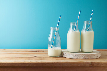 Milk bottles on wooden table over blue background