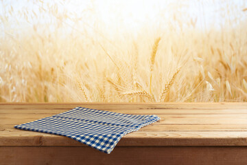 Empty wooden table with tablecloth over wheat field blurred background