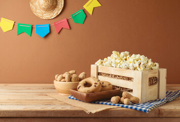 Festa Junina party background with popcorn, peanuts and decoration on wooden table. Brazilian...