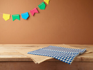 Brazilian Festa Junina summer harvest festival concept. Empty wooden table with tablecloth over wall  background. Mock up for design and product display
